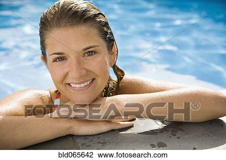 Stock Image - Smiling Hispanic woman standing in swimming pool. Fotosearch