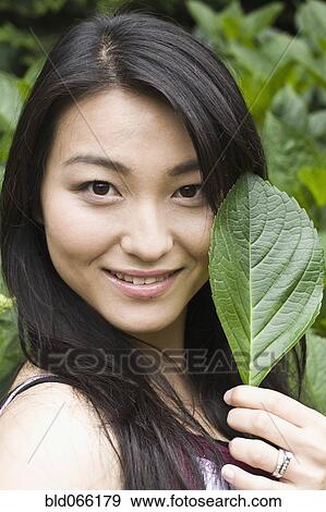 Stock Photo - Smiling Japanese woman holding leaf. Fotosearch