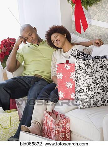 Tired African man sitting on sofa with girlfriend and shopping bags View Large Photo Image Stock Image - Tired African man sitting on sofa with girlfriend and shopping bags. Fotosearch