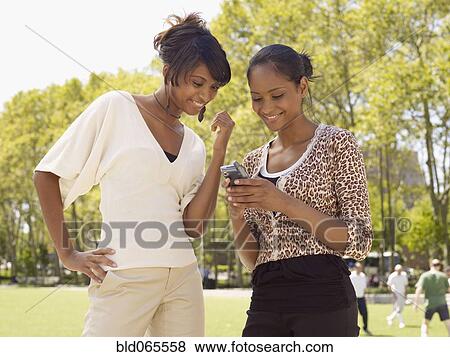Woman looking at friend’s cell phone View Large Photo Image Stock Photo - Woman looking at friend’s cell phone. Fotosearch