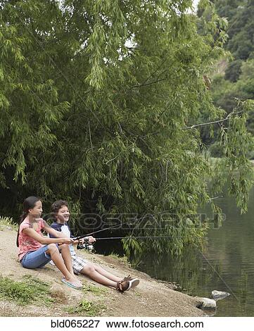Stock Photo - Young boy and girl fishing in lake. Fotosearch