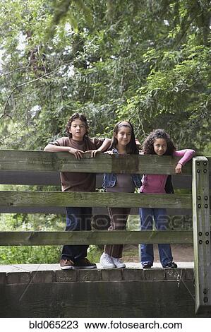 Stock Image - Young friends posing on wooden bridge. Fotosearch