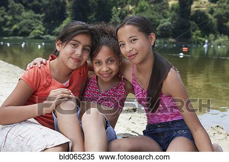 Stock Photography - Young girl friends hugging near lake. Fotosearch