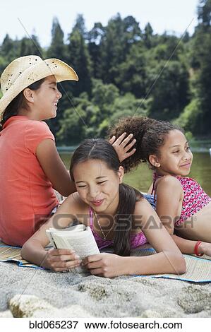 Stock Photo - Young girl friends playing on beach near lake. Fotosearch