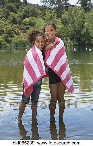 Stock Photo - Young girls wading in lake with towel. Fotosearch