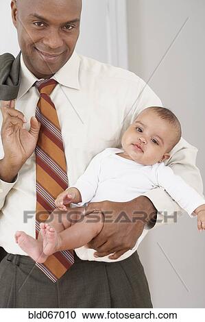 Stock Image - African father cradling baby daughter. Fotosearch
