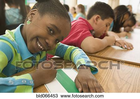 Stock Image - African school girl writing on name card. Fotosearch