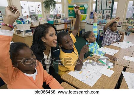 Stock Photo - African students raising hands in classroom. Fotosearch