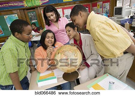 Stock Photograph - African teacher and students looking at globe. Fotosearch