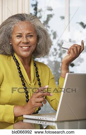 Stock Image - African woman shopping online at home. Fotosearch