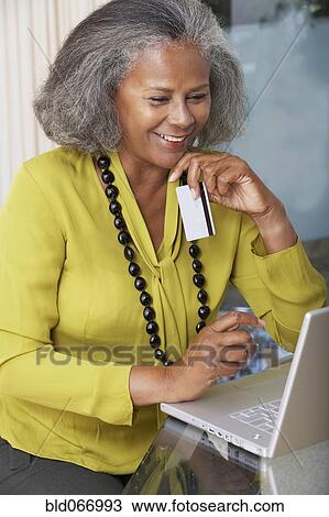 Stock Image - African woman shopping online at home. Fotosearch