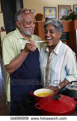 Stock Photo - African woman tasting husband’s cooking. Fotosearch