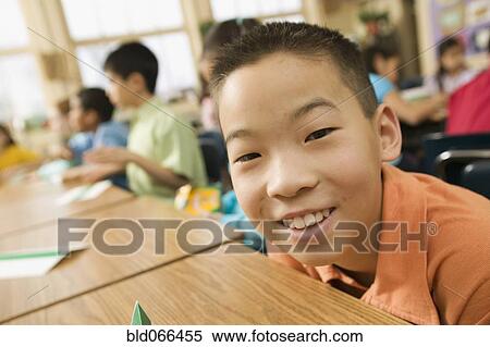 Stock Photography - Asian school boy sitting at desk. Fotosearch