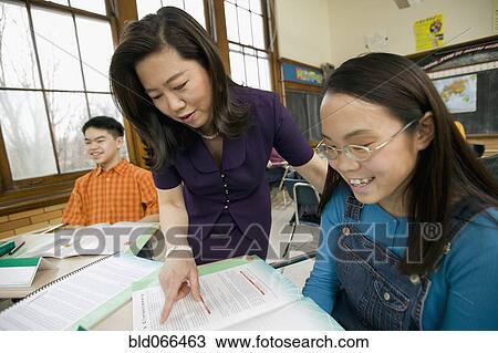Stock Image - Asian school teacher helping student. Fotosearch