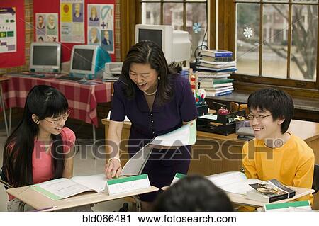 Stock Image - Asian school teacher helping students. Fotosearch
