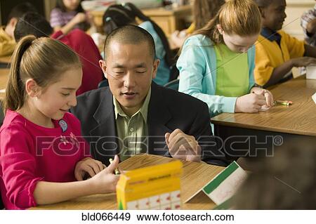 Stock Photo - Asian school teacher helping students. Fotosearch