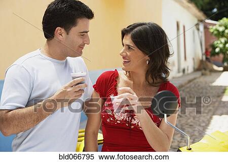 Stock Photography - Couple drinking together near scooter. Fotosearch