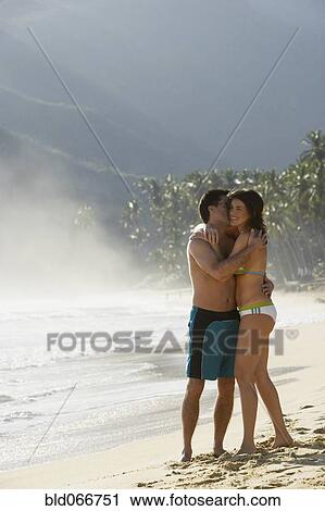 Stock Image - Couple hugging on beach. Fotosearch