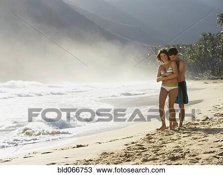 Stock Image - Couple hugging on beach. Fotosearch