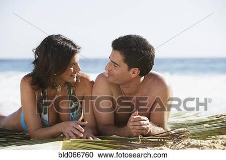 Stock Image - Couple laying on beach. Fotosearch