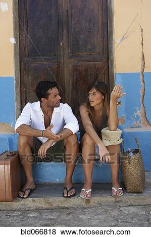 Stock Photo - Couple sitting with suitcases arguing. Fotosearch