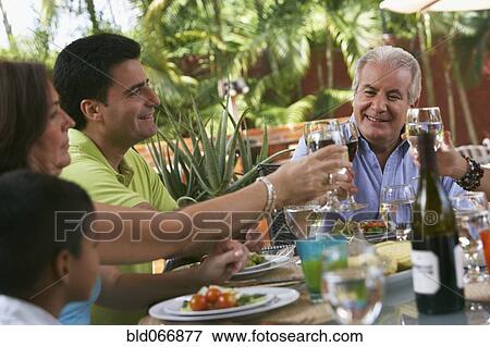Stock Photo - Family enjoying healthy lunch and drinking red wine. Fotosearch