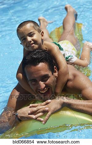 Picture - Father giving son piggyback ride in swimming pool. Fotosearch