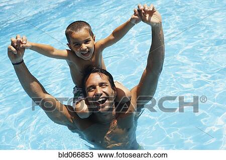 Stock Image - Father giving son piggyback ride in swimming pool. Fotosearch