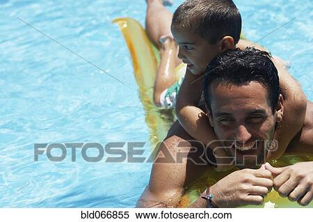 Stock Photography - Father giving son piggyback ride in swimming pool. Fotosearch