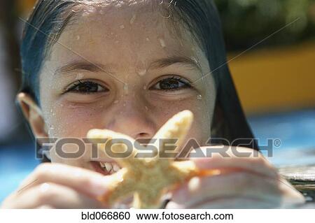 Stock Image - Girl holding starfish in swimming pool. Fotosearch