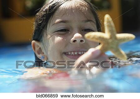 Stock Photo - Girl holding starfish in swimming pool. Fotosearch