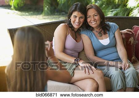 Stock Image - Girl taking photograph of mother and grandmother. Fotosearch