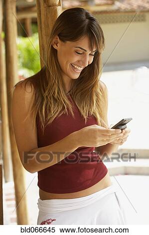 Stock Photography - Happy woman texting on cell phone. Fotosearch