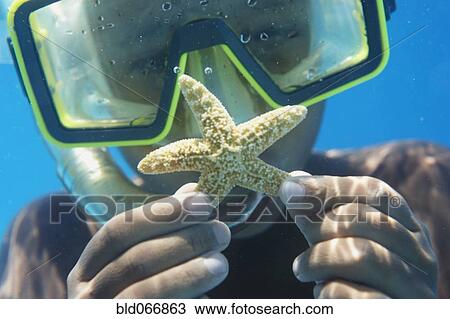 Stock Image - Hispanic boy in goggles holding starfish. Fotosearch