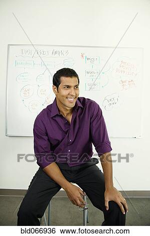 Stock Photograph - Hispanic businessman sitting near whiteboard. Fotosearch