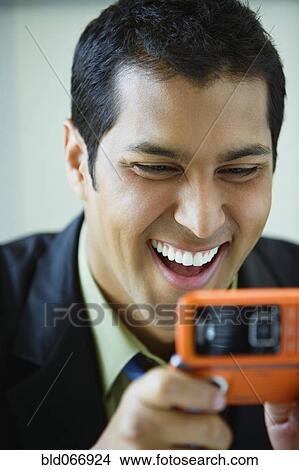 Picture - Hispanic businessman text messaging on cell phone. Fotosearch