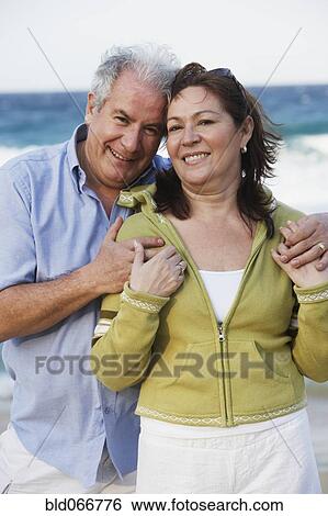 Stock Photograph - Hispanic couple hugging on beach. Fotosearch