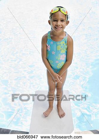 Stock Photo - Hispanic girl in bathing suit standing on diving board. Fotosearch