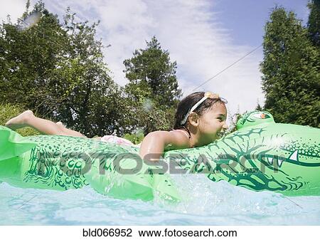 Stock Image - Hispanic girl playing in swimming pool. Fotosearch