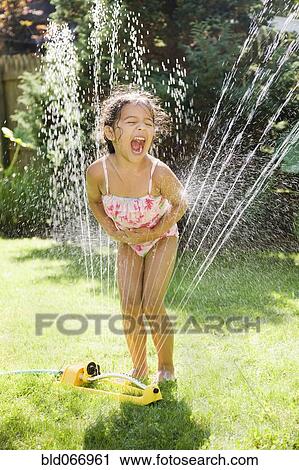 Hispanic girl playing in water sprinkler View Large Photo Image Stock Image - Hispanic girl playing in water sprinkler. Fotosearch