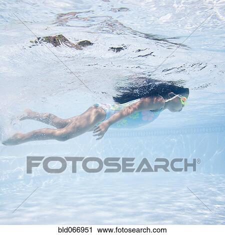 Stock Image - Hispanic girl swimming in pool. Fotosearch