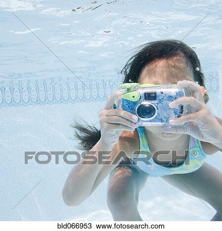 Stock Image - Hispanic girl taking photograph underwater. Fotosearch