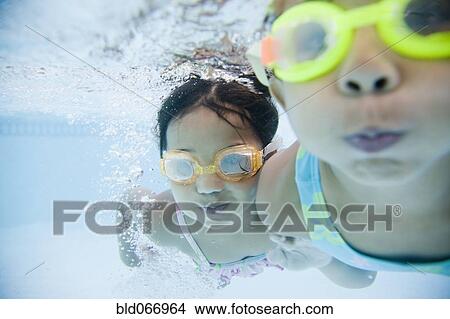 Picture - Hispanic girls swimming underwater in pool. Fotosearch