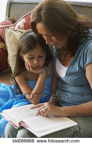 Stock Photo - Hispanic grandmother reading to granddaughter. Fotosearch