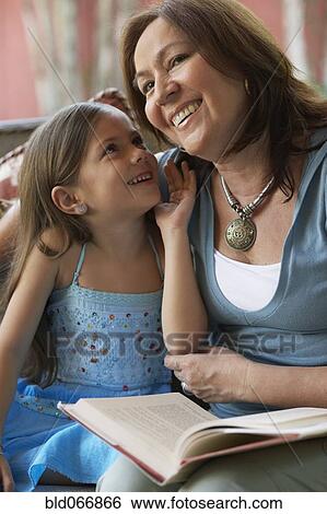 Stock Photograph - Hispanic grandmother reading to granddaughter. Fotosearch