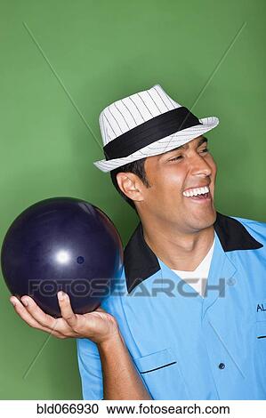Stock Image - Hispanic man holding bowling ball. Fotosearch