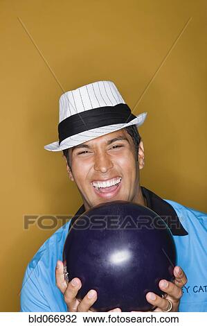 Stock Image - Hispanic man holding bowling ball. Fotosearch