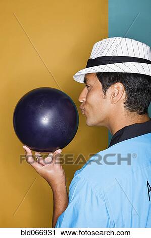 Stock Image - Hispanic man kissing bowling ball. Fotosearch