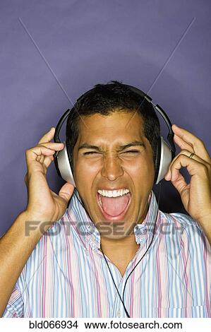 Picture - Hispanic man listening to headphones. Fotosearch