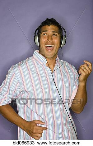 Stock Image - Hispanic man listening to headphones. Fotosearch